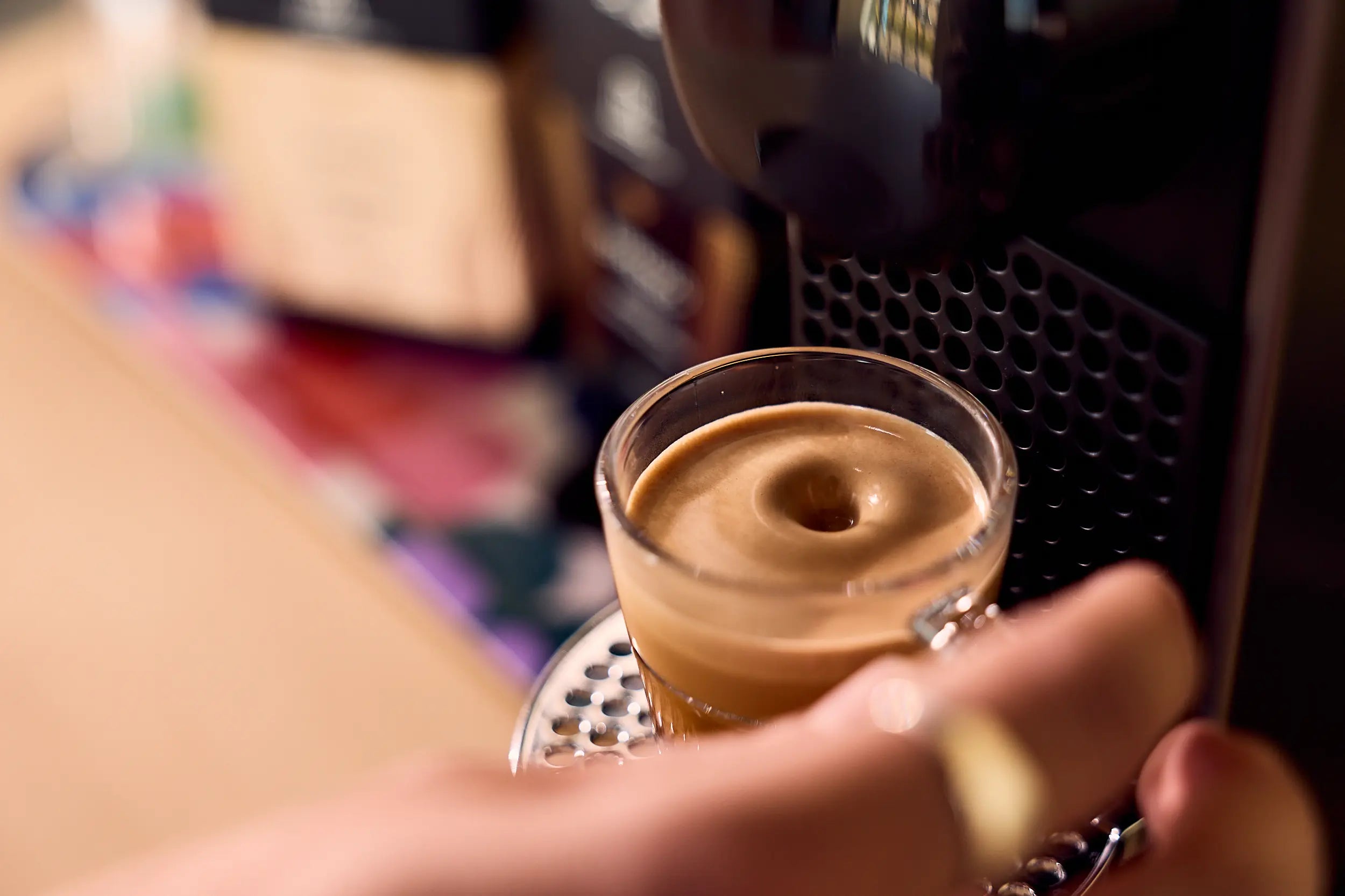 ViCAFE coffee capsule espresso pouring shot with Nespresso® machine in the background.